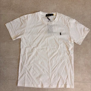 Vit t-shirt från Polo Ralph Lauren - Klassisk vit t-shirt från Polo Ralph Lauren med liten broderad logga på bröstet. T-shirten har rund halsringning och korta ärmar. Perfekt basplagg för garderoben.