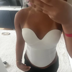 Vit axelbandslös korsettopp - Säljer en vit axelbandslös korsettopp med sweetheart-urringning. Strl 70C