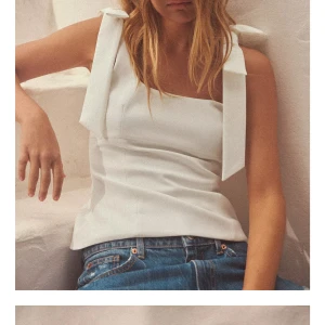 Vit topp Zara  - Säljer en stilren vit topp med breda axelband som knyts i stora rosetter. Toppen har en rak passform och är tillverkad i ett slätt material. Perfekt att styla med jeans eller kjol för en fräsch look. Från Zara i storlek xs