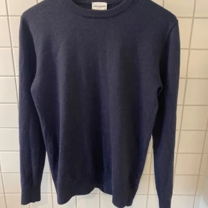 Mörkblå merinoulltröja från John Henric - Säljer en klassisk mörkblå tröja från John Henric i 100% merinoull. Tröjan har rund halsringning och långa ärmar, perfekt för lite kyligare sommarkvällar. Enkel och stilren design som passar till mycket.