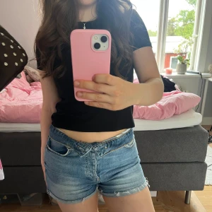Blå jeansshorts från Gina Tricot - Snygga blå jeansshorts med råa kanter och klassisk femficksdesign. Shortsen har låg midja och en avslappnad passform. Perfekta för varma dagar och enkla att matcha med olika toppar.