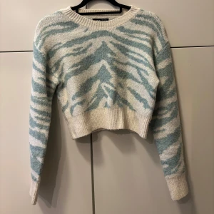 Zebramönstrad stickad tröja - Säljer en supermjuk, croppad, stickad tröja med zebramönster i ljusblått/turkos och vitt. Perfekt till ett par jeans eller på myskvällen! Storlek  S.