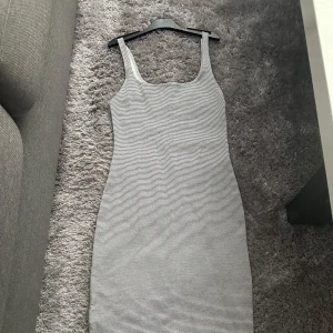 Randig ribbad klänning från Zara  - Säljer en smalrandig, ribbad klänning från Zara  i svart och vitt. Klänningen är ärmlös med rundad halsringning och har en kroppsnära passform. Perfekt för dig som gillar enkel och stilren design. Klänningen är använd max 3 gånger.