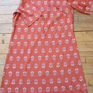 Rostfärgad klänning med geometriskt mönster - Säljer en rostfärgad klänning med vitt geometriskt mönster och korta ärmar. Klänningen har en klassisk krage och dragkedja i ryggen. Perfekt för dig som gillar retrostil och unika prints.Retro klänning 🍊🥭🍊🥭  97cm lång  Armhåla till armhåla 51cm Stretchig   Råa kanter   Dragkedja baktill   