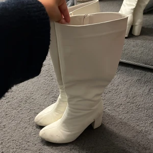 Vita boots - Säljer ett par vita höga stövlar med blockklack. Stövlarna har dragkedja på insidan och perfekta för att lyfta vilken outfit som helst. stl: 38 klackhöjd: 7 cm 