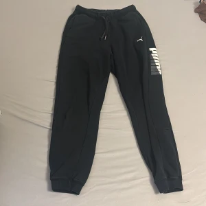 Svart Tracksuit från Puma - Säljer en svart hoodie från Puma med stor logga i vitt på bröstet. Tröjan har huva med dragsko och en stor magficka framtill. Perfekt för dig som gillar sportig och avslappnad stil. ( finns hål vid vänstra handleden och vid midjan men syns knappt)