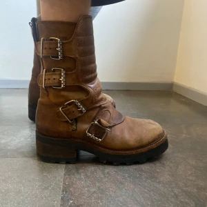 Bruna boots från Buffalo - Säljer ett par bruna boots från Buffalo med tre dekorativa spännen på sidan och grov sula. De har även brutits för storlek 41 med sockor :-P  Köpta vintage i Köpenhamn och har älskat dom sen dess.