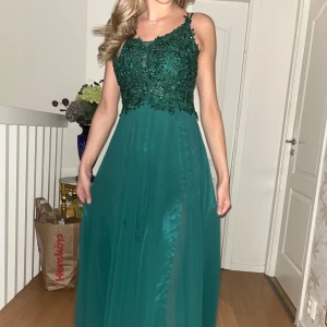 Mörkgrön klänning - Mörkgrön detaljerad klänning med ett glittrigt blommönster på överdelen, använd 1 gång i bra skick och är justerbar, storlek XS/S