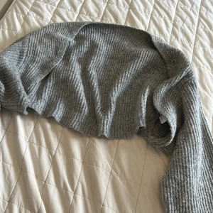 Grå ribbad bolerotopp - Säljer en grå ribbad bolerotopp med lång ärm. Perfekt att slänga över en topp eller klänning för extra värme och stil. Mjuk och stretchig, passar till många outfits.