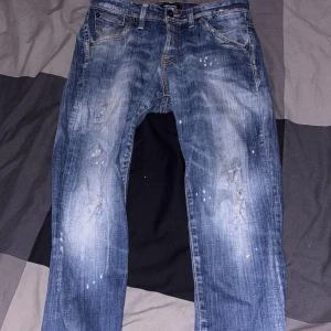 Blå jeans från Jack & Jones - Snygga blå jeans från Jack & Jones med klassisk femficksmodell med raka ben och normal passform. Jeansen har detaljer som synliga sömmar och en liten italiensk flaggdetalj vid linningen.