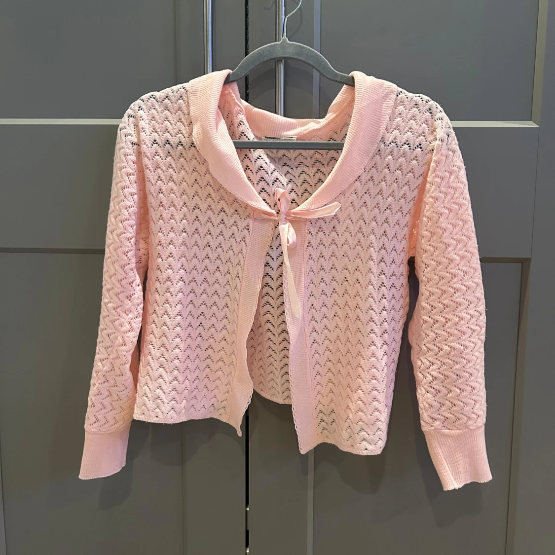 Ljusrosa stickad kofta med rosett från Courtelle