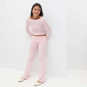 Ljusrosa yoga pants - Säljer ett par ljusrosa bootcut yoga pants med låg midja. Byxorna har en mjuk och stretchig känsla, perfekt för en avslappnad och trendig look. Passformen är tight upptill och utsvängd nertill. Superfina att styla med en matchande topp.