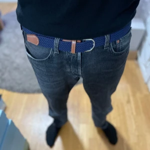 Blått flätat bälte med bruna skinn-detaljer - Snyggt blått flätat bälte med detaljer i brunt skinn och silverspänne. Perfekt accessoar för att lyfta din outfit. Passar till jeans och chinos. Enkel att justera för bästa passform. Nytt skick! Aldrig använt!