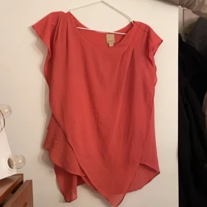 Korallrosa omlott blus - Säljer en snygg korallrosa blus från Anna Field med omlott-detalj framtill. Blusen har korta ärmar och en lös, flowy passform som ger en chill och trendig vibe. Perfekt för dig som gillar färg och vill sticka ut lite extra.