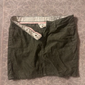 Olivgrön manchesterkjol från H&M - Snygg olivgrön kortkjol i manchester från H&M. Klassisk femficksmodell med knapp och dragkedja framtill, samt bälteshällor. 