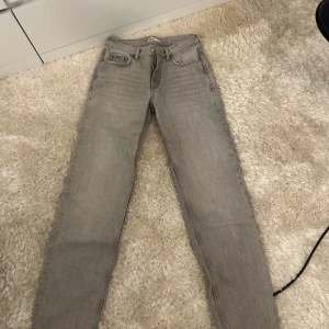 Grå raka jeans - Säljer ett par grå jeans med rak passform och klassisk femficksdesign. Jeansen har normal midja och är tillverkade i denim. Perfekta för en clean och stilren look.