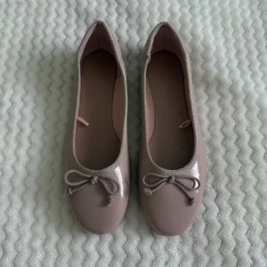 Rosa ballerinaskor med rosett - Snygga rosa ballerinaskor med rund tå och rosett framtill. Skorna är glansiga och passar till mycket. Nypris 325:-. 