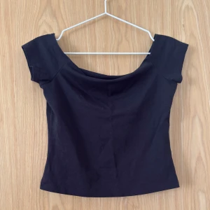 Svart offshoulder topp från BikBok - En svart offshoulder topp från BikBok i mjuk bomull. Toppen har korta ärmar och en snygg, croppad passform. Perfekt att styla med jeans eller kjol etc. 