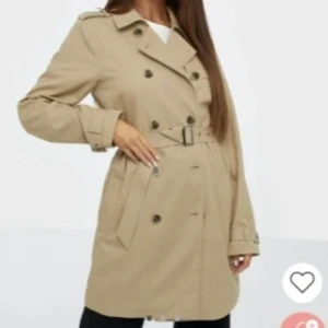 Trenchcoat Vila - Trenchcoat med bälte från Vila i nyskick. Tunnt material 