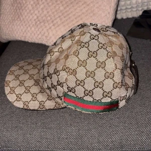 Gucci keps  - Hej säljer denna Gucci keps beig, finns en slitning på framsidan som syns p bilderna annars inget annat, 2021 modell, vilket innebär att kepsen inte kan bli solbränd, såklart ÄKTA, storlek M ! 
