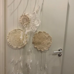 Drömfångare fem stycken alla på bilden ingår .  - Bilderna visar en handgjord väggdekoration med virkade dukar och fjädrar,  drömfångare i mjuka detaljer. Inrednings detaljer . Allt görs av mig . Hobby . Mvh Ida 
