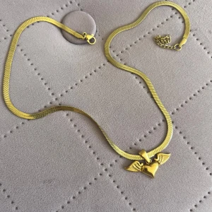 Halsband hjärta med vingar  - Säljer mitt guldfärgade halsband med ett hjärta och vingar. Knappt använt 