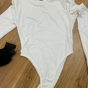 2-pack långärmade bodys från SHEIN - Två stilrena långärmade bodys från SHEIN i storlek S, en i vitt och en i svart. Båda har rund halsringning och knäppning i grenen. Tillverkade i mjukt och stretchigt material som sitter snyggt på kroppen. Perfekta att styla med jeans eller kjol.