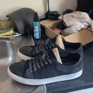 Marinblå sneakers från Lanvin med lackad tå - Snygga marinblåa sneakers från Lanvin med klassisk vit sula och cool lackad tå i svart. Ovandelen är i mocka och skorna har grå snörning. Perfekta för dig som gillar stilrena men ändå unika detaljer. Har gjort dom vita med whiting cream 50 kr för halva whitning creamen