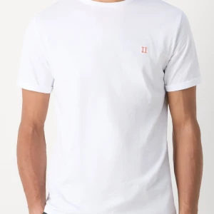 Vit t-shirt från LES DEUX  - Klassisk vit t-shirt i bomull med korta ärmar och en liten broderad detalj i rött på bröstet. Enkel och stilren design som passar till det mesta. Skön passform och mjukt material. Från LES DEUX
