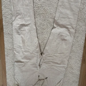 Beiga linnebyxor från Dressmann XL - Snygga beiga linnebyxor från Dressmann i storlek XL. Byxorna har dragsko i midjan och raka ben, tillverkade i en skön linneblandning. Perfekta för varma dagar när du vill ha en avslappnad men stilren look.