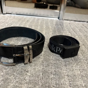 Svart Armani/Peak Performance Bälte - Säljer ett svart skärp från Armani i äkta skinn, och ett svart Peak Performance bälte i tyg. Armani bältet är aldrig använt, däremot är Peak bältet använt några gånger. 300kr för båda. 250kr för Armani. 100kr för Peak Performance. 