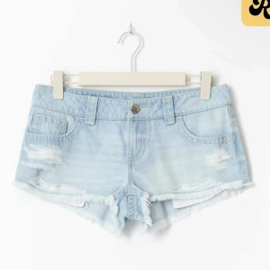 Ljusblå slitna jeansshorts - Snygga ljusblå jeansshorts med slitna detaljer och fransig kant. Klassisk femficksmodell med låg midja och knappstängning. Perfekta för varma dagar och ger en avslappnad vibe. Wow💕