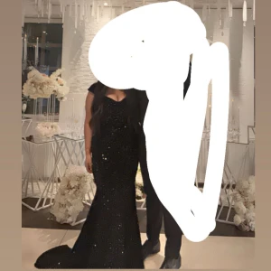 Svart glittrig långklänning  - Supersnygg svart långklänning från Paparazzi, täckt med glittriga paljetter. Klänningen har ärmlös design, markerad midja och v-ringning. Den har en elegant, figurnära passform som breddas nertill för en dramatisk look. Perfekt för bal eller fest! Nypris 2000kr  jag kan skicka bild på hur den ser ut på vid intresse