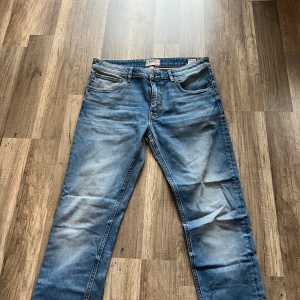 Crocker 302 Skinny jeans blå 33/32 - Snygga blå jeans från Crocker, modell 302 Skinny. Klassisk femficksdesign med skinny passform och normal midja. Jeansen har slitningar och ljus tvätt för en cool, avslappnad look. Perfekta för dig som gillar smalare jeans med modern känsla.