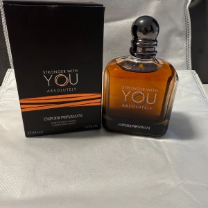 Emporio Armani Stronger With You Absolutely - Emporio Armani Stronger With You Absolutely är en herrparfym i en elegant, fyrkantig glasflaska med mörk bärnstensfärg och svart rund kork. Förpackningen är svart med orange detaljer och rymmer 100 ml. Doften är intensiv och modern, perfekt för dig som gillar exklusiva parfymer.