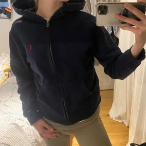 Marinblå hoodie från Ralph Lauren - Hej säljer denna snygga zip-upp hoodie från Ralph lauren då den tyvärr inte kommer till användning längre. Köpt på kidsbrandstore så storlek L/G - 160/80 skulle säga att det motsvarar en xs/s❤️ Om jag minns rätt nypris när jag köpte den var ca 1100, priset är inte spikat i sten, går alltid att diskutera men vill ändå sälja för någorlunda ☺️☺️