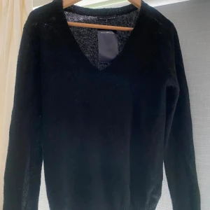 Svart v-ringad tröja Brandy Melville - Oanvänd, Svart, stickad tröja från Brandy Melville med v-ringning och långa ärmar. Enkel och stilren modell som är perfekt att slänga på sig över ett linne eller t-shirt. 