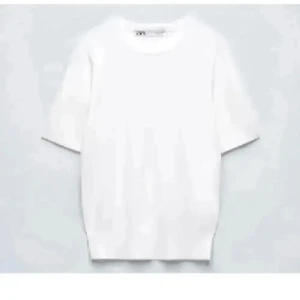 Vit basic t-shirt från Zara - En klassisk vit t-shirt från Zara med rund hals och korta ärmar. Enkel och stilren design i mjuk bomull, perfekt till jeans eller shorts. Passar dig som gillar en clean och fräsch look.