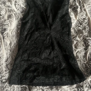 Svart spetsblus från Gina Tricot XS - Supersnygg svart blus från Gina Tricot i storlek XS. Toppen är ärmlös och har ett vackert spetsmönster över hela plagget. Perfekt för dig som gillar en elegant och trendig look med lite extra detaljer.