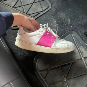 Valentino Open sneakers vit/rosa skinn - Snygga Valentino Open sneakers i vitt skinn med en bred rosa rem över mitten och coola nitar på hälen.  Lite slitna men mycket är smuts därav priset