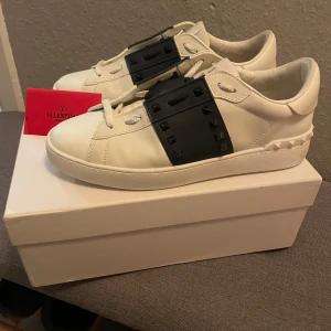 Valentino Garavani Open sneakers vit/svart - Snygga Valentino Garavani Open sneakers i skinn med stiliga nitar över skon. Kommer med originalkartong och dustbag. Bara att höra av er vid frågor. Vid snabb affär så kan vi diskutera pris