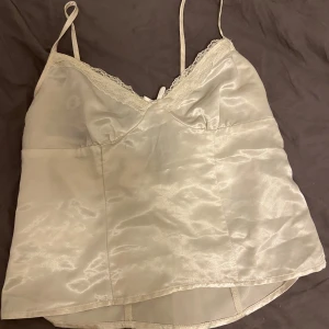 Vit satinlinne från h&m - Säljer ett elegant vitt satinlinne från h&m. Linnet har tunna axelband och spetsdetaljer vid halsringningen. Perfekt för en stilren look. Xs men mer som xxs, köpt för 349 och den har använts två gånger!