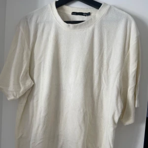 Vit t-shirt i frotté - Säljer en stilren vit t-shirt från 157. Den har en klassisk rund hals och korta ärmar, perfekt för en enkel och avslappnad look. Materialet känns mjukt och bekvämt mot huden och är i frotté. Nypris: 299kr