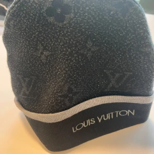 Svart och grå mössa - Snygg grå mössa med ikoniskt mönster och broderad logga. Perfekt för att hålla stilen i kallare väder.