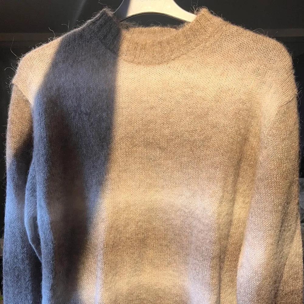En beige och brun oscar jacobson tröja gjort av alpackablanding. Ny pris 2299. Neuletakit & Villapaidat.
