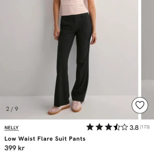Svarta lågmidjade kostymbyxor från Nelly - Snygga svarta kostymbyxor från Nelly med låg midja och utsvängda ben. Perfekta för en stilren look. Byxorna har en klassisk design med dragkedja och hällor för bälte. Perfekt längd för en som är 170+, kom privat för bättre bilder💞
