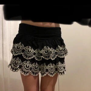 Svart kortkjol med spetsdetaljer - Snygg svart mini kjol med vita spetsdetaljer i i jätte fint skick perfekt för sommaren! ❤️( den säljs inte längre) den är i storlek 14 år ca xs och passar mig som är s/xs ❤️