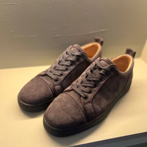 Gråa mocka skor med röd sula  - Säljer dessa feta Loubs, perfekta inför sommaren. Säljer dem pga att de inte är min stil längre men vill passera dem vidare till dig. Självklart är dem använda men ända slitaget som märks är på sulan. Priset är inte hugget i sten 