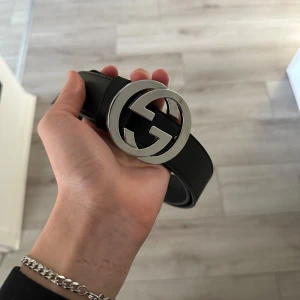 Svart bälte med silver logga - Helt ny bälte fick den för några dagar sen, har använt en gång bara och det kan märkas. Det är riktig läder och jätte bra kvalité på den