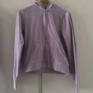 Ljuslila hoodie med dragkedja - Säljer en mysig ljuslila hoodie med dragkedja och huva. Tröjan har långa ärmar och en praktisk ficka framtill. Perfekt för en avslappnad stil.